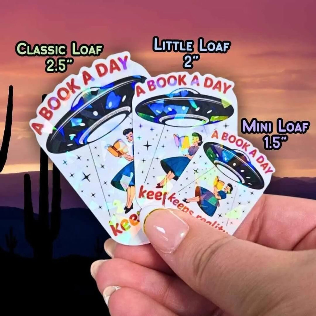 A Book A Day Keeps Reality Away – Holographic Book Lover Sticker, Alien UFO Abduction Reading Sticker, Bookish Sticker, Sci - Fi Reader Gift - Holographic Sticker | The TabbyLoaf