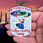 A Book A Day Keeps Reality Away – Holographic Book Lover Sticker, Alien UFO Abduction Reading Sticker, Bookish Sticker, Sci - Fi Reader Gift - Holographic Sticker | The TabbyLoaf